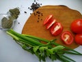 Freshly cut celery, tomatoes, green onion on wooden cutting board next to spiced dill and black pepper Royalty Free Stock Photo