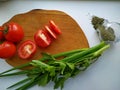 Freshly cut celery, tomatoes, green onion on wooden cutting board next to spiced dill Royalty Free Stock Photo