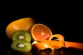 Freshly Cut Orange, Kiwi, Pink Grapefruit, Orange Peel and Knife on Dark Wet Background