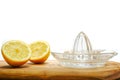 Freshly cut yellow lemon and glass juicer on a wooden board. White background Royalty Free Stock Photo