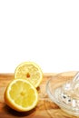 Freshly cut yellow lemon and glass juicer on a wooden board. White background Royalty Free Stock Photo