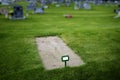 Freshly Dug Grave in Cemetery with Headstones and Green Grass