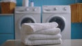 Freshly folded towels with laundry machines in blue-tiled room Royalty Free Stock Photo