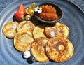 Freshly fried pancakes with cloudberry jam served on a blue dish on a bright sunny day closeup. Royalty Free Stock Photo