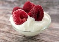 Freshly frozen raspberries with white yogurt in a glass cup on a wooden table Royalty Free Stock Photo