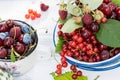 Freshly gathered juicy red currants, cherries, raspberries, blueberries in white plate and cup in garden on sunny day close up Royalty Free Stock Photo