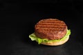 Freshly grilled plant based burger patty on bun with lettuce and sauce isolated on black surface. Copy space Royalty Free Stock Photo