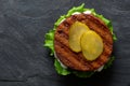 Freshly grilled plant based burger patty on bun with lettuce, slices of gherkin and sauce isolated on black slate. Top view. Copy Royalty Free Stock Photo