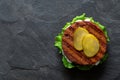 Freshly grilled plant based burger patty on bun with lettuce, slices of gherkin and sauce isolated on black slate. Top view. Copy Royalty Free Stock Photo