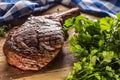 Freshly grilled tomahawk steak on slate plate with salt pepper rosemary and parsley herbs