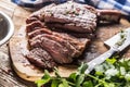 Freshly grilled tomahawk steak on slate plate with salt pepper rosemary and parsley herbs. Sliced pieces of juicy beef steak