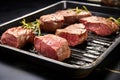 freshly grilled venison steaks resting on a steel tray