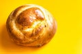 Freshly home baked artisan Easter sweet bread bun on bright yellow background. Coffee pastry. Holiday baking breakfast morning