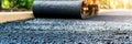 Freshly laid asphalt texture, roller finishing paved surface smoothly on blurred background. Royalty Free Stock Photo