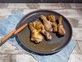 Freshly cooked chicken drumsticks, on a gray round plate, denim napkin and cutlery on a light background. Royalty Free Stock Photo