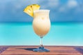 Freshly made pinacolada cocktail with straw on wooden table ocean background at the beach