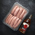 Freshly made raw butchers sausages in skins with Sanford orchards apple cider, Devon, United Kingdom, March 20, 2019.