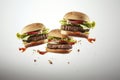 Freshly made three burgers fall on gray background. Creative concept of floating fast food. Background of falling burgers.