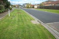 Freshly mown grass at a nature strip on a suburban road with some residential houses in the distance. Royalty Free Stock Photo