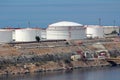 Freshly Painted New Large Industrial White Metal Oil Refinery Tanks On Top Of Rocky Sea Shore Connected With Metal Pipes To Pier