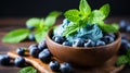 Freshly picked blueberries and spearmint leaves arranged in a rustic clay bowl on a wooden table