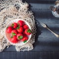 Freshly picked juicy organic strawberries in ceramic bowl on rustic black wooden kitchen table lightened by morning window light. Royalty Free Stock Photo