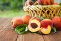 Freshly picked peaches in basket on a brown wooden table. Ripe peaches in a wicker basket, green garden on the background Royalty Free Stock Photo