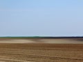 Freshly ploughed brown and sand color farm land with hills