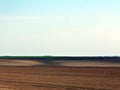 Freshly ploughed undulating hills of brown and sand color farm land with hills