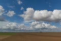 Freshly plowed farm field and blue sky with clouds