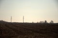 Freshly plowed field and power line with pillars passing through it. Landscape