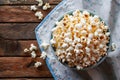 Freshly popped popcorn in bowl on rustic wooden table with blue striped cloth Royalty Free Stock Photo