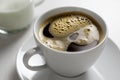 Freshly poured black coffee with froth in white ceramic cup next