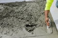 On a freshly poured concrete sidewalk, a worker holds a steel trowel in the process of smoothing it out and leveling it Royalty Free Stock Photo