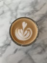 A freshly prepared cup of cortado against a marble background