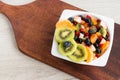 Freshly prepared fruit vitamin healthy salad of kiwi, tangerine, apple, cranberries, blueberries, grapes in a white bowl on a kitc Royalty Free Stock Photo