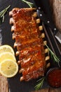 Freshly prepared grilled pork ribs with chili sauce and lemon close-up on a slate board. Vertical top view Royalty Free Stock Photo