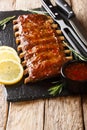 Freshly prepared grilled pork ribs with chili sauce and lemon close-up on a slate board. vertical Royalty Free Stock Photo