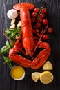 Freshly prepared lobster closeup with lemon, garlic, fresh tomatoes and herbs on a table. Vertical top view Royalty Free Stock Photo