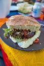 Freshly prepared sandwich served on a plate, atop a yellow tablecloth