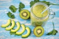 Avocado smoothie with kiwi and banana and two halves of a kiwi on blue wooden table. Diet vegetarian food. Raw foods. Royalty Free Stock Photo