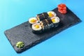 Freshly prepared sweet mango sushi roll served on a black plate over blue background Royalty Free Stock Photo