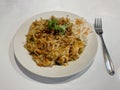 Freshly prepared Thai fried noodles with chicken and vegetables garnished with coriander and peanuts on a white plate. Royalty Free Stock Photo