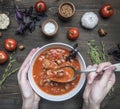 Freshly prepared tomato soup with basil, garlic and onion, thyme and seasonings, in a white plate, girl scooped up a spoon, on Royalty Free Stock Photo