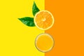 Freshly pressed citrus fruits juice in glass cut in half orange with green leave on duotone yellow background background