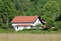 Freshly renovated suburban family house with new roof tiles and white facade surrounded with dense forest in back