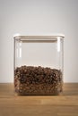 Freshly roasted coffee beans in airtight plastic container on wood table