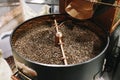 The freshly roasted coffee beans from a large old coffee roaster being stirred in the cooling cylinder. Fresh coffee beans