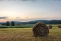 Freshly rolled bales of hay rest on a field at sunrise Royalty Free Stock Photo
