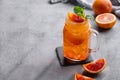 Freshly squeezed blood orange juice with ice, mint and a slice of fruit in a jar on a blue background with citrus fruits and